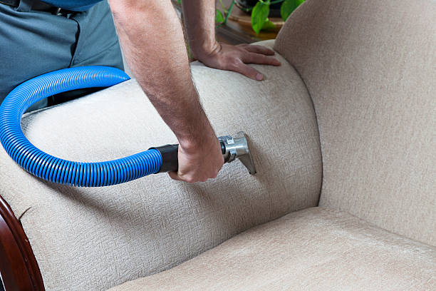 man vacuuming sofa with vacuum