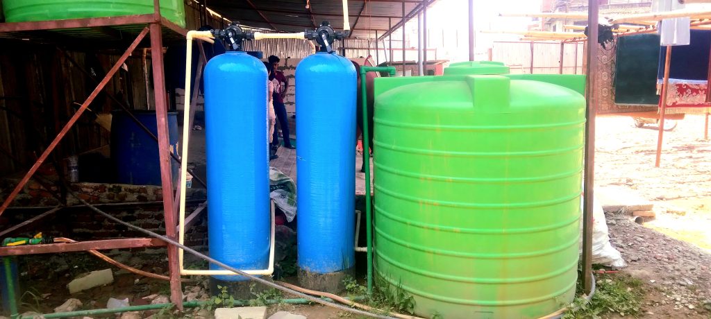 two blue cylindrical borewell water treatment plant with 2 green rooftop water tank